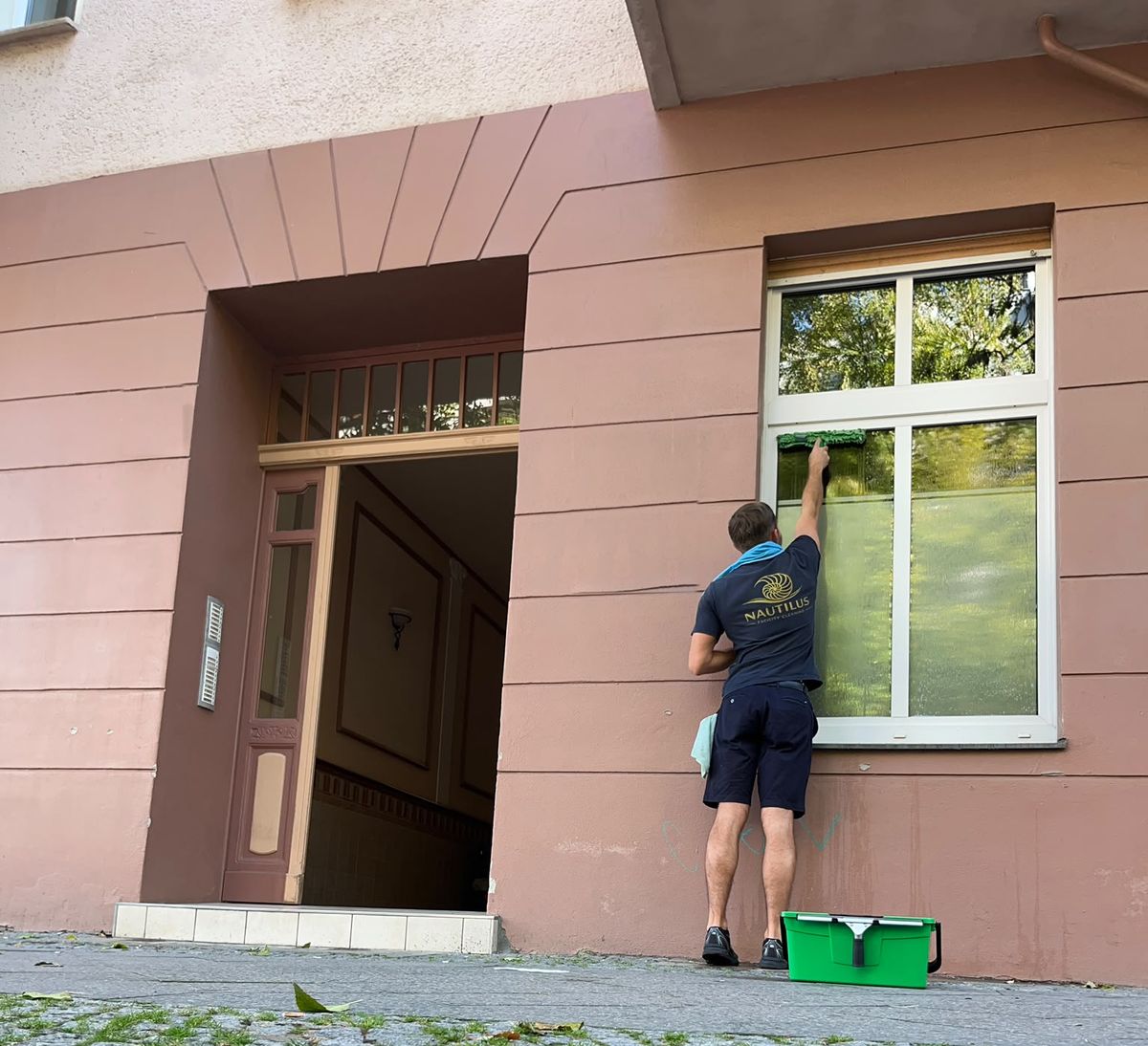 Philipp De Boer, Inhaber von Nautilus Facility Cleaning, bei der Fensterreinigung von Hand vom Gehweg aus